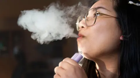 0a3eedf0-3d36-11f0-83bc-05219e34eab3 0a3eedf0-3d36-11f0-83bc-05219e34eab3 Getty Images A young person exhaling smoke from a vape, which she is holding in her hand. Disposable vapes ban unlikely to reduce appeal, says campaigner 0a3eedf0 3d36 11f0 83bc 05219e34eab3