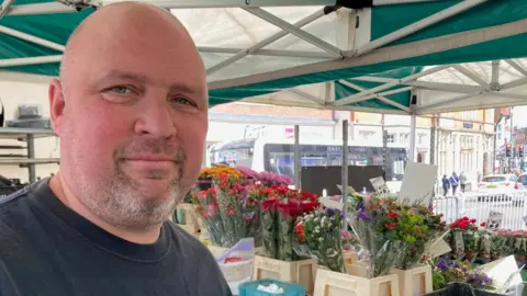 9e0589e0-241d-11f0-a5a8-bd6ffba156c1 9e0589e0-241d-11f0-a5a8-bd6ffba156c1 Chris Ilsley stands at his plant stall at Epsom market with cut flowers ready to sell behind him. shops could be forced to accept cash in future, mps warn Shops could be forced to accept cash in future, MPs warn 9e0589e0 241d 11f0 a5a8 bd6ffba156c1