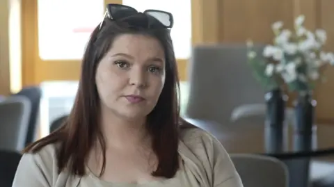ffe5cd80-2776-11f0-9ade-51d827e59e40 ffe5cd80-2776-11f0-9ade-51d827e59e40 Jamie Niblock/BBC Ellena Baxter a woman with brown hair who is wearing a cream coloured outfit. She is looking towards the camera and is sitting at a table. 'Doctors told my mum poison symptoms were anxiety' ffe5cd80 2776 11f0 9ade 51d827e59e40