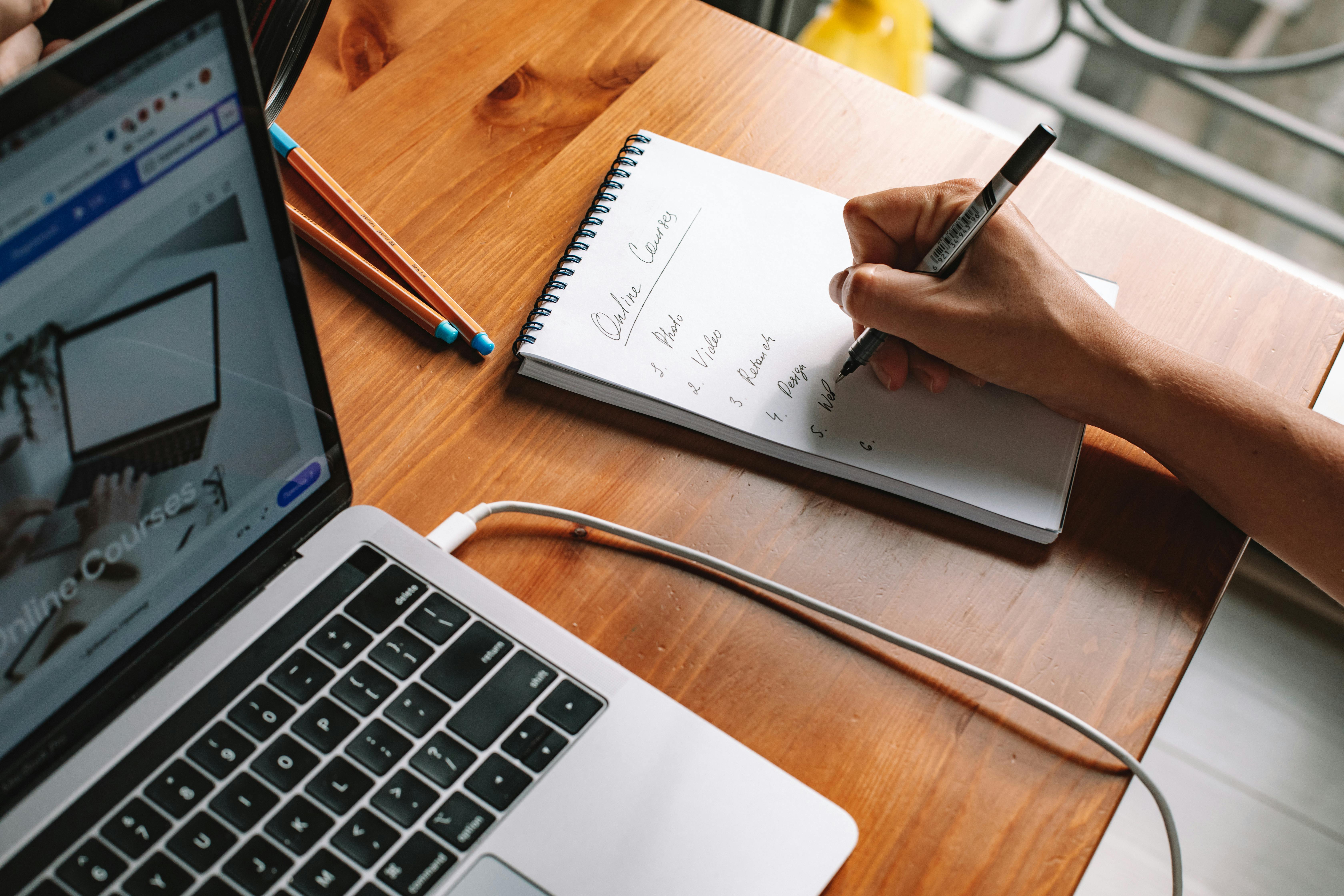 Pen writing on pad with laptop  40+ of the best MIT courses you can take online for free hero image