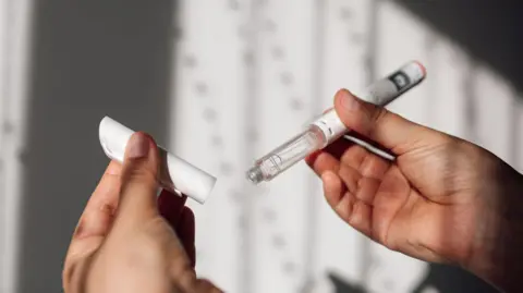 14daf3f0-526a-11f0-8485-7bd50fa63665 14daf3f0-526a-11f0-8485-7bd50fa63665 Getty Images Close up of hands holding a vial containing clear liquid with its cap off. Weight loss jabs study begins after reports of pancreas issues 14daf3f0 526a 11f0 8485 7bd50fa63665