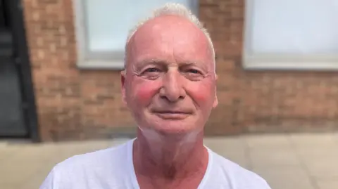 4b357250-54d0-11f0-bbb4-7b9a23219fce 4b357250-54d0-11f0-bbb4-7b9a23219fce Mousumi Bakshi/BBC Paul Davis is looking at the camera with a light smile. He is wearing a white T-shirt and has short grey hair. He is standing in front of a red bricked building. Lotus has 'no plans' to close any car factory 4b357250 54d0 11f0 bbb4 7b9a23219fce