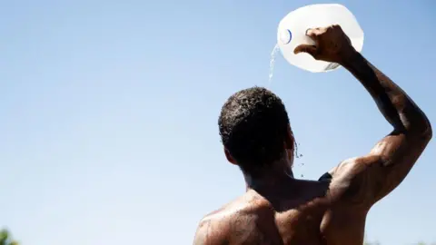 531e1d50-2596-11f0-88f6-794ae336edff 531e1d50-2596-11f0-88f6-794ae336edff Getty Images A man pours water from a large container on his head on a sunny day. Why we need 'revolutionary' cooling tech 531e1d50 2596 11f0 88f6 794ae336edff