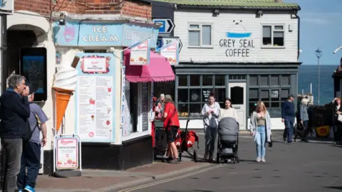 Getty Images People walk along a street and pass an ice cream parlour   Heatwave likely as yellow heat health alerts issued in England a0aae0b0 4b77 11f0 86d5 3b52b53af158