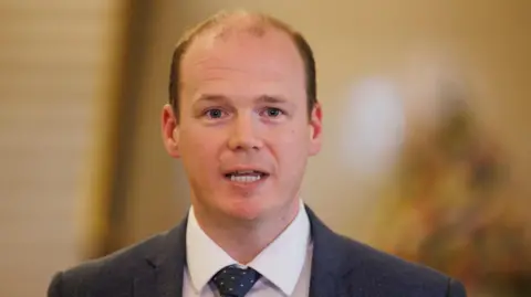 bc630640-4611-11f0-8402-c958f7234d20 bc630640-4611-11f0-8402-c958f7234d20 PA A balding man with blue eyes mid speech with a yellowy blurred background behind him. He is wearing a white shirt, navy tie with pink spots on it and a navy blazer. Winter fuel payment scammers already 'targeting pensioners' bc630640 4611 11f0 8402 c958f7234d20