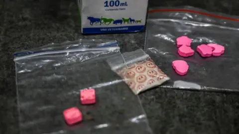d12afbe0-46b7-11f0-98c9-f388968ae068 d12afbe0-46b7-11f0-98c9-f388968ae068 Getty Images A stock image of some illegal drugs including two bags with pink tablets inside and a bag of white powder in a plastic baggy with smiley faces on How to stay safe at festivals this summer d12afbe0 46b7 11f0 98c9 f388968ae068