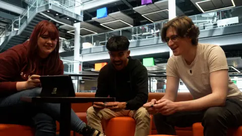 df21eb30-50ff-11f0-86d5-3b52b53af158 df21eb30-50ff-11f0-86d5-3b52b53af158 BBC News Kady, Dirk and Nicholas sit on orange sofas playing a multiplayer game together on Nintendo Switch. They're laughing and smiling during a tense race. 'New video games cost me a whole day's wages' df21eb30 50ff 11f0 86d5 3b52b53af158