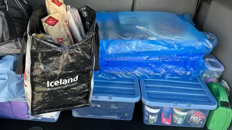 The interior of a van boot with blue lidded plastic crates of food and clothing, crates of baked goods wrapped in blue plastic and a bag full of sandwiches are piled on top  &#039;It&#039;s heartbreaking leaving women sleeping rough&#039; 09778970 5caa 11f0 b8c6 458cd8075fd5