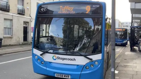 0aa58450-5cb9-11f0-ae37-a7df7603ca40 0aa58450-5cb9-11f0-ae37-a7df7603ca40 BBC A photo of a blue and white Stagecoach bus parked on a road next to a lamp post. Another bus is parking behind and people are sat in a shelter by the side of the road Public transport 'too costly' for young people 0aa58450 5cb9 11f0 ae37 a7df7603ca40