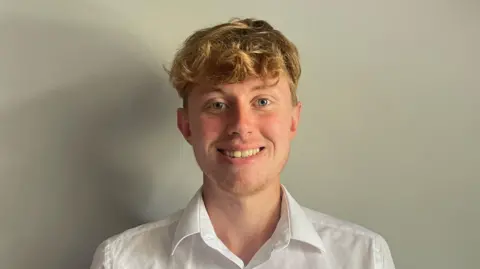 1cf0fac0-5cbb-11f0-8be8-0332ffa2eeb4 1cf0fac0-5cbb-11f0-8be8-0332ffa2eeb4 Gloucestershire Community rail Partnership A photo of a white man with blond hair and wearing a white shirt. He is stood in front of a grey wall Public transport 'too costly' for young people 1cf0fac0 5cbb 11f0 8be8 0332ffa2eeb4
