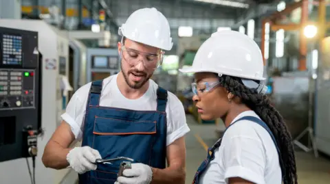 Getty Images A male and female engineer both wearing white hard hats discussing a piece of machinery  Reeves disappointed after economy unexpectedly shrinks 32df56d0 5e44 11f0 be82 117161087dc9