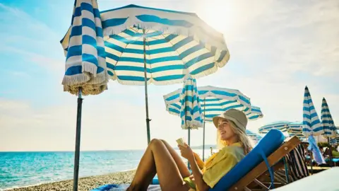 4217adb0-4b6a-11f0-86d5-3b52b53af158 4217adb0-4b6a-11f0-86d5-3b52b53af158 Getty Images A woman sits on a sun lounger under a sun umbrella on a beach. What should you look for when choosing sunscreen? 4217adb0 4b6a 11f0 86d5 3b52b53af158