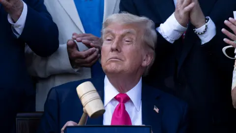 44cd78f0-598e-11f0-9074-8989d8c97d87 44cd78f0-598e-11f0-9074-8989d8c97d87 Getty Images Donald Trump wearing dark suit with a vibrant pink tie, confidently holding up a gave. He is surrounded by people applauding. This is a photo opp after he signed the "Big Beautiful Bill Act" at the White House in Washington, DC, on July 4, 2025. US debt is now $37tn – should we be worried? 44cd78f0 598e 11f0 9074 8989d8c97d87