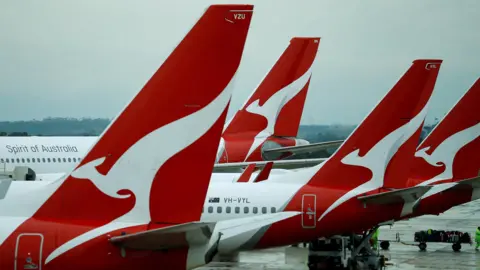 4f928950-56dd-11f0-960d-e9f1088a89fe 4f928950-56dd-11f0-960d-e9f1088a89fe Reuters Four planes are lined up in a row on the tarmac of an aiport, each with the Qantas logo of a stylized white kangaroo on a red background emblazoned on the tail. Qantas data breach exposes up to six million customer profiles 4f928950 56dd 11f0 960d e9f1088a89fe