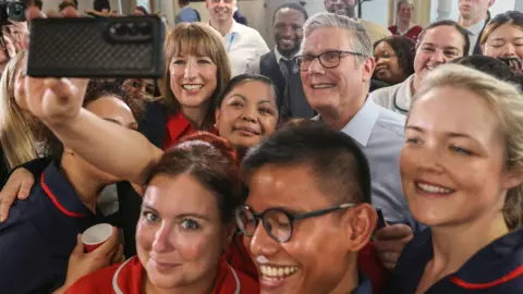 672cd130-5825-11f0-988d-abc8933015ea 672cd130-5825-11f0-988d-abc8933015ea PA Media Close up Sir Keir Starmer and Rachel Reeves posing for a selfie taken by an NHS staff member. They are smiling and surrounded by a group of NHS staff all smiling at the camera Seven ways Starmer's plan could change the NHS 672cd130 5825 11f0 988d abc8933015ea