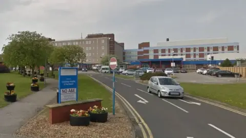 6e41a030-58a8-11f0-a912-539e30409bd3 6e41a030-58a8-11f0-a912-539e30409bd3 Google Entrance to University Hospital of Hartlepool. There is a patch of green grass on the verge of the road with an 80s-design hospital building in the background. No date for restarting baby deliveries at hospital 6e41a030 58a8 11f0 a912 539e30409bd3