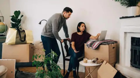 9ffdd980-58f9-11f0-8b18-17952be0e8b0 9ffdd980-58f9-11f0-8b18-17952be0e8b0 Getty Images Man and woman look at laptop in a living room surrounded by cardboard boxes. The woman is sitting on a dining chair, the man is standing behind her, leaning on the back of her chair, the laptop is on top of a big cardboard box. Excellent or awful – why Lifetime ISAs divide opinion 9ffdd980 58f9 11f0 8b18 17952be0e8b0