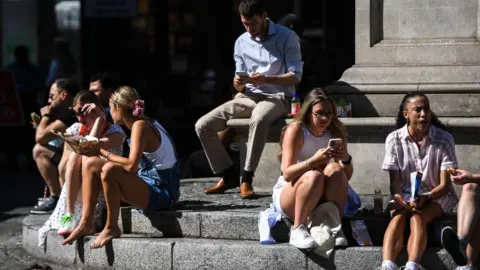 c032eb60-24d2-11f0-9341-7dd5c259f730 c032eb60-24d2-11f0-9341-7dd5c259f730 Getty Images Men and women sit on the steps of a fountain in the sunshine while eating their lunch and checking their phones. A number of women are wearing shorts. What are UV levels and how can you protect yourself? c032eb60 24d2 11f0 9341 7dd5c259f730