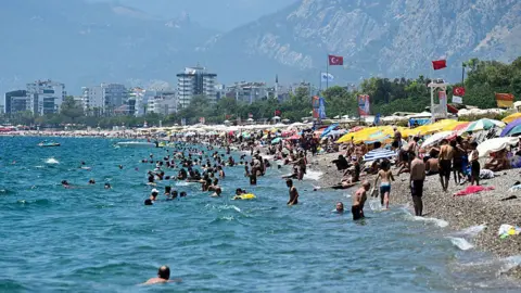 d30a4fd0-5bd7-11f0-84a3-9b39642a4f3b d30a4fd0-5bd7-11f0-84a3-9b39642a4f3b Getty Images A beach in Turkey where lots of people are sunbathing under umbrellas, and many other people are swimming in the sea Holidays to Spain, Cyprus and Turkey soar in price d30a4fd0 5bd7 11f0 84a3 9b39642a4f3b