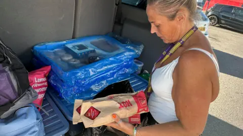 A woman in a white vest packing sandwiches in brown bags into a shopping bag in the boot of a van  &#039;It&#039;s heartbreaking leaving women sleeping rough&#039; db2ad4d0 5bde 11f0 b5c5 012c5796682d