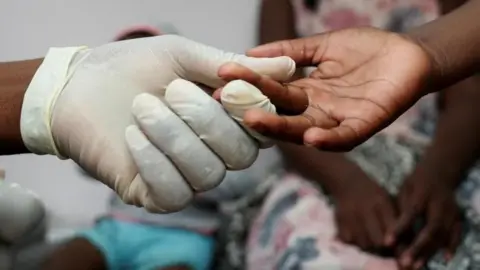 f3bc2cb0-5cbf-11f0-a847-6f5cde5d04a4 f3bc2cb0-5cbf-11f0-a847-6f5cde5d04a4 Reuters A glove-wearing nurse takes a blood sample from a child for an HIV test while the child's mother looks on at a clinic in Diepsloot, north of Johannesburg, South Africa, 12 March2025 The US helped successfully tackle Aids – now cuts put that at risk f3bc2cb0 5cbf 11f0 a847 6f5cde5d04a4